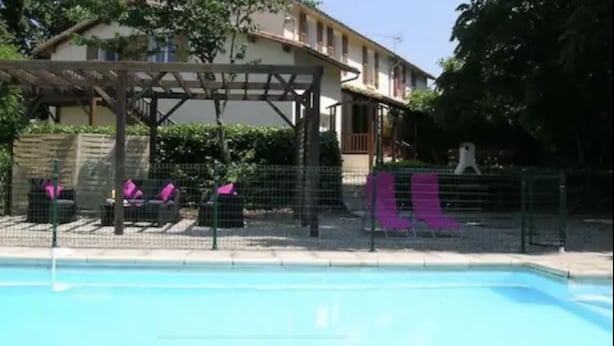 A swimming pool with a covered seating area and a building in the background. - Les Roseries Boutique Gite with Garden and Pool (CLUSSAIS LA POMMERAIE)