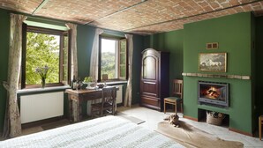 A room with a brick ceiling, green walls, a fireplace, a large wooden cabinet, and a window with curtains. - Tenuta Cà dei Mandorli (Castel Boglione)