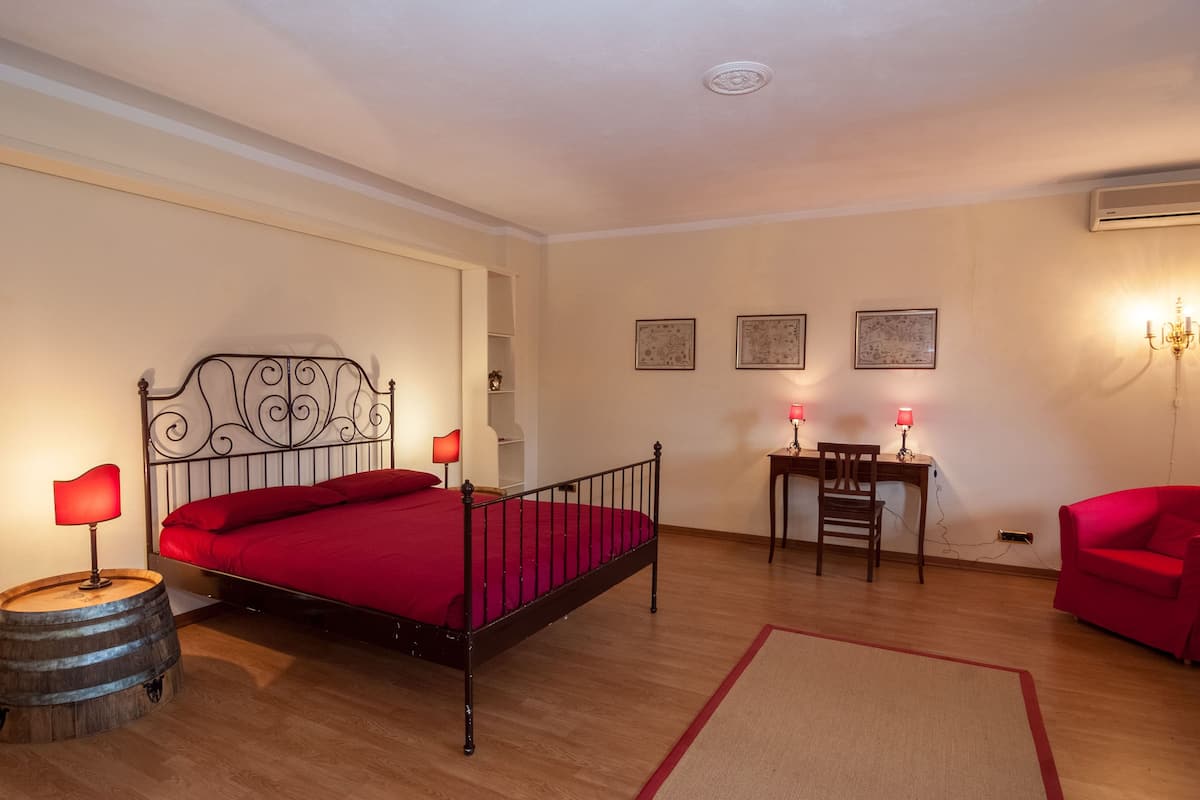 Ein Schlafzimmer mit Bett, Schreibtisch, Stuhl und einem roten Sofa.