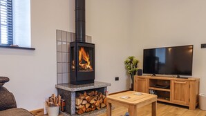 A modern living room with a stone fireplace, a television, and a wooden cabinet.