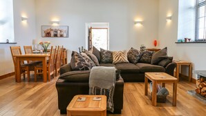 A modern living room with a sectional sofa, wooden coffee table, and a dining area with chairs and a table.