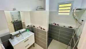 A modern bathroom with a white vanity, a large mirror, and a shower area.