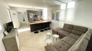 A modern living room with a large sofa, a small coffee table, and a kitchen area in the background.