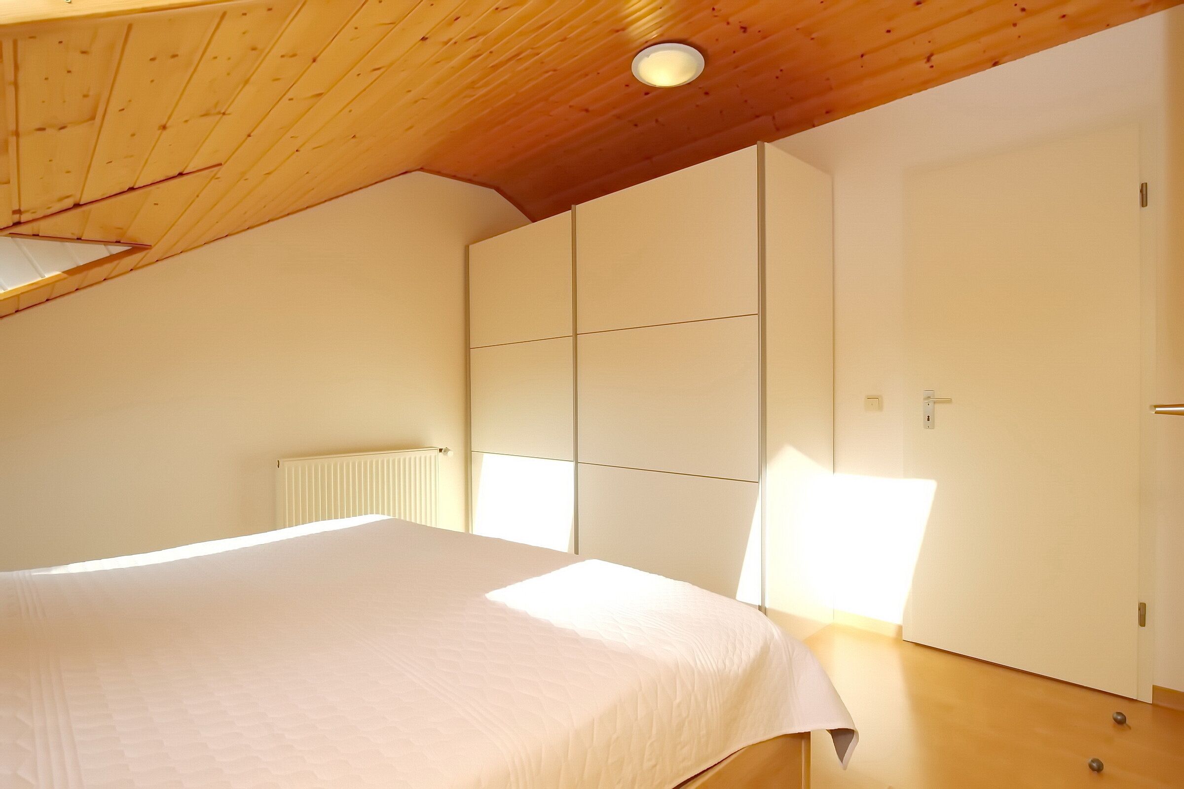 Una camera da letto con un letto, un armadio e un termosifone.
