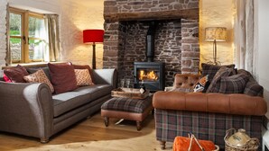 A cozy living room with a stone fireplace, a sofa set, and a lamp.