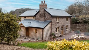 A stone house with a sloped roof and a wooden extension.