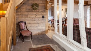 A wooden staircase leading to a living area with a plaid sofa and a chair.