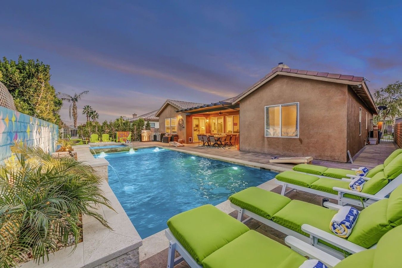 A swimming pool with lounge chairs, a barbecue area, and a building with a patio.