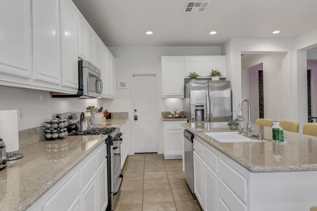 A modern kitchen with white cabinetry, stainless steel appliances, and a granite countertop.