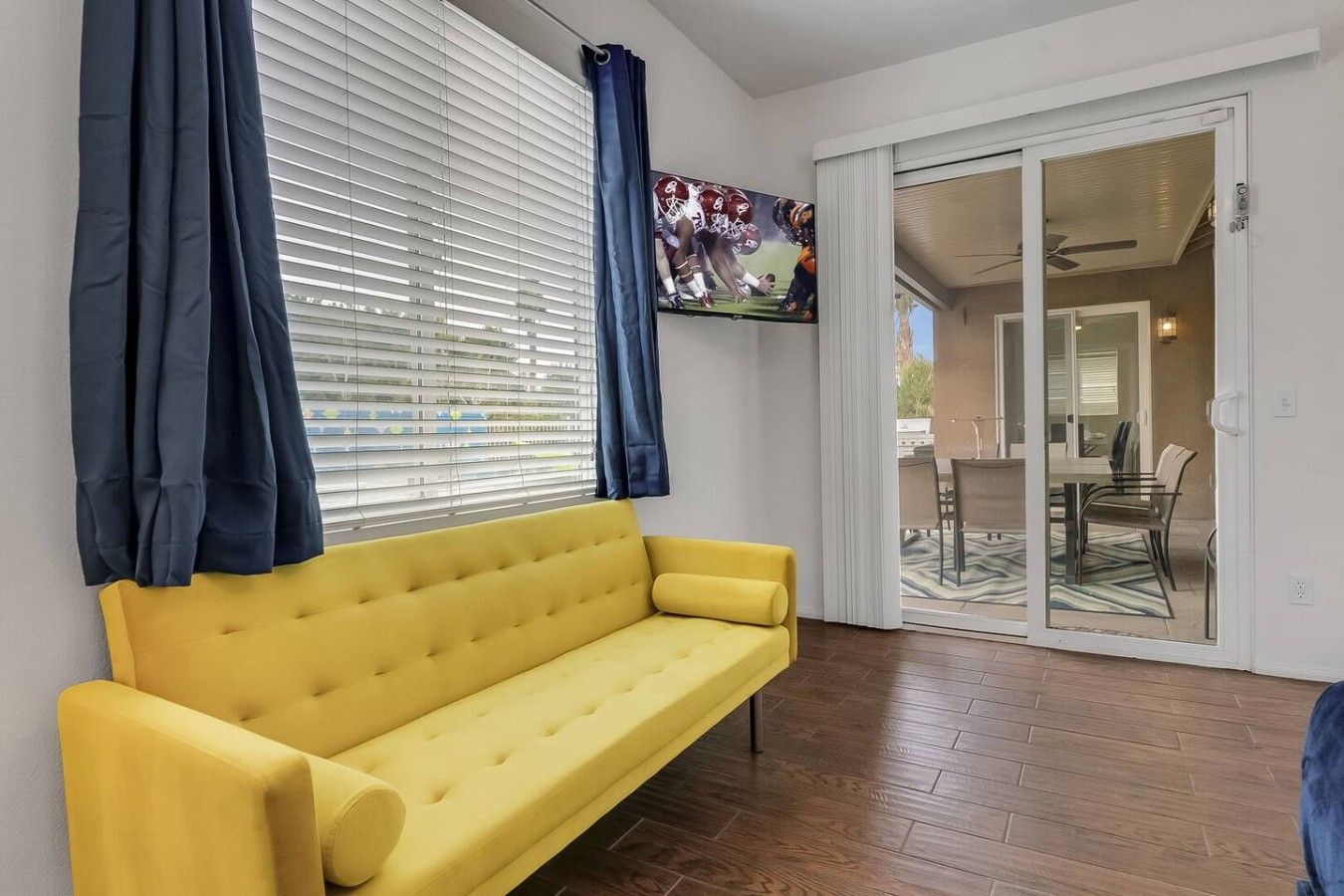 A yellow sofa in a room with a sliding glass door leading to an outdoor area.