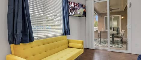 Un canapé jaune dans une pièce dotée d’une porte-fenêtre coulissante donnant sur un espace extérieur.