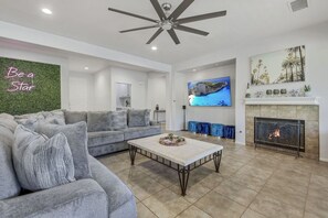 A living room with a gray sofa, a coffee table, a fireplace, and a TV mounted on the wall.