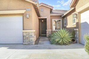 A residential house with a garage, a stone accent wall, and a large agave plant in the front yard.