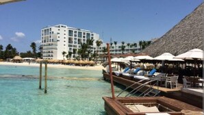 Un hôtel situé en bord de mer, doté d’une piscine, de chaises longues et de parasols.
