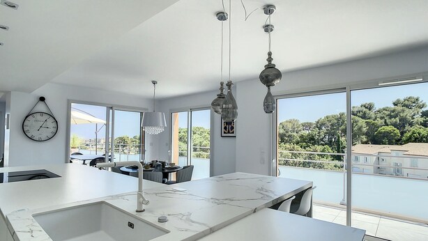 A modern kitchen with a large island, a dining area with a table and chairs, and a view of the outdoors.