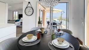 A modern dining area with a chandelier, a clock, and a view of the outdoors.