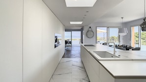 A modern kitchen with a central island, a built-in oven, and a large window providing a view of the outdoors.