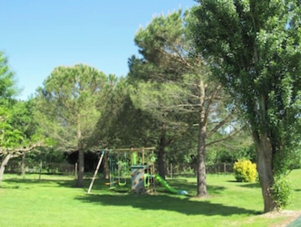 A playground with swings and slides, surrounded by trees and grass. - BOYER BAS COTTAGE (2–10 people) With Private Pool (Saint-Gaudéric)