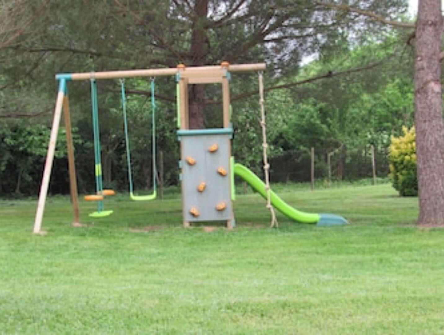 Une aire de jeux avec des balançoires, un toboggan et des prises d’escalade.