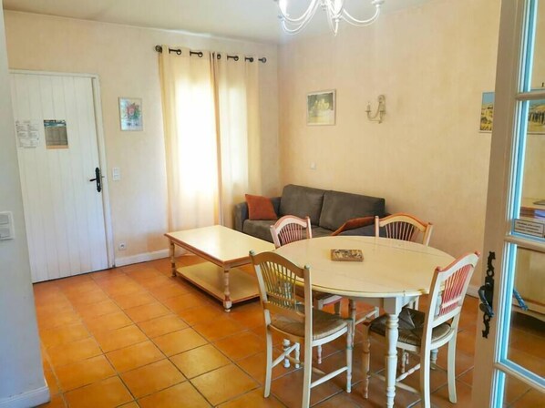 A dining area with a round table and four chairs, a sofa, and a door with a white frame.