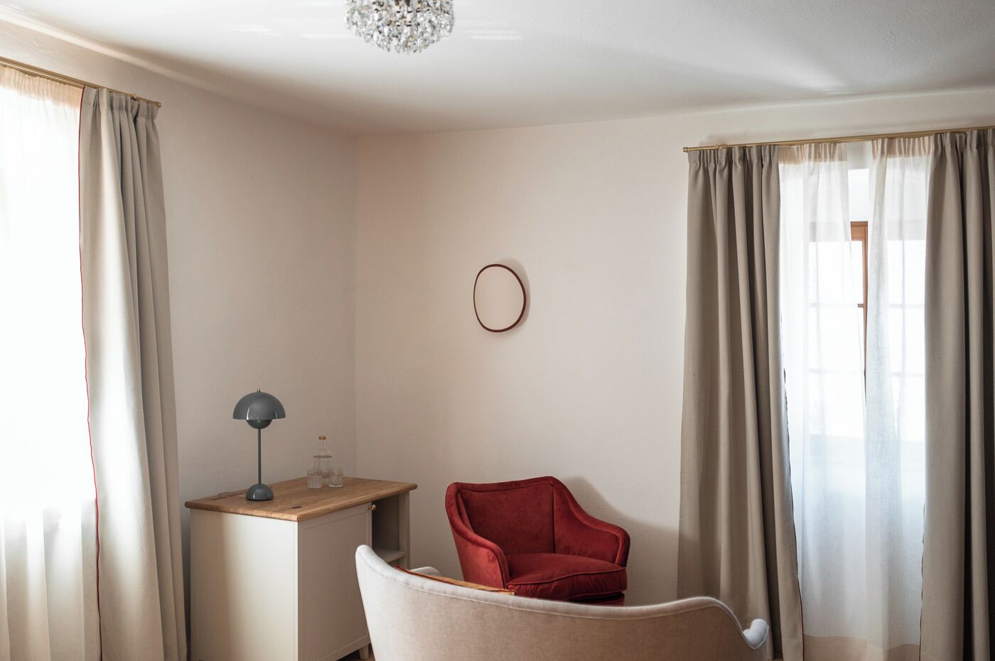 Una habitación con un escritorio, una silla roja y un espejo redondo en la pared.