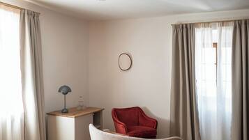 Una habitación con un escritorio, una silla roja y un espejo redondo en la pared.