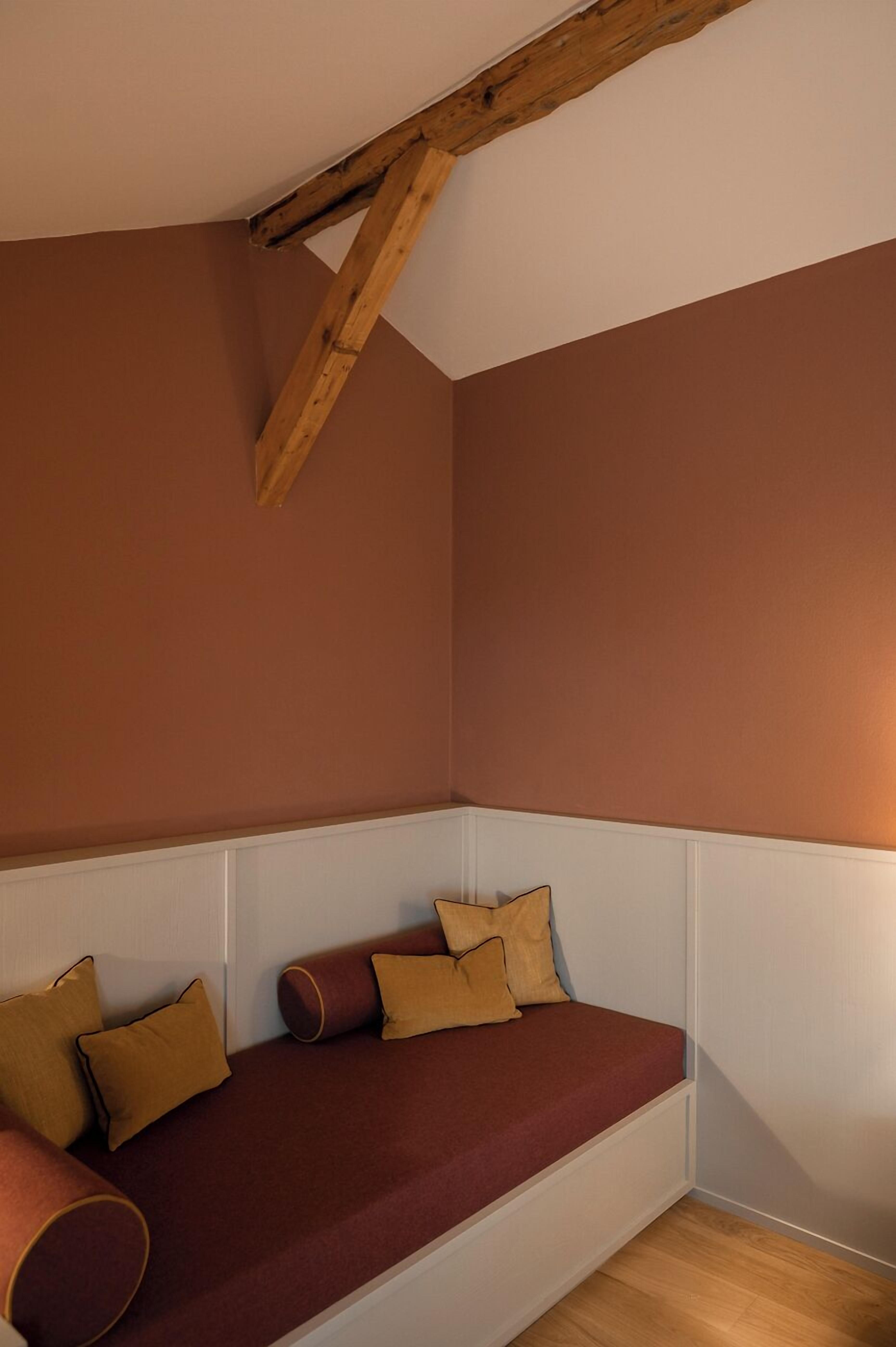 A corner room with a built-in bench, wooden beams, and a white wainscoting.