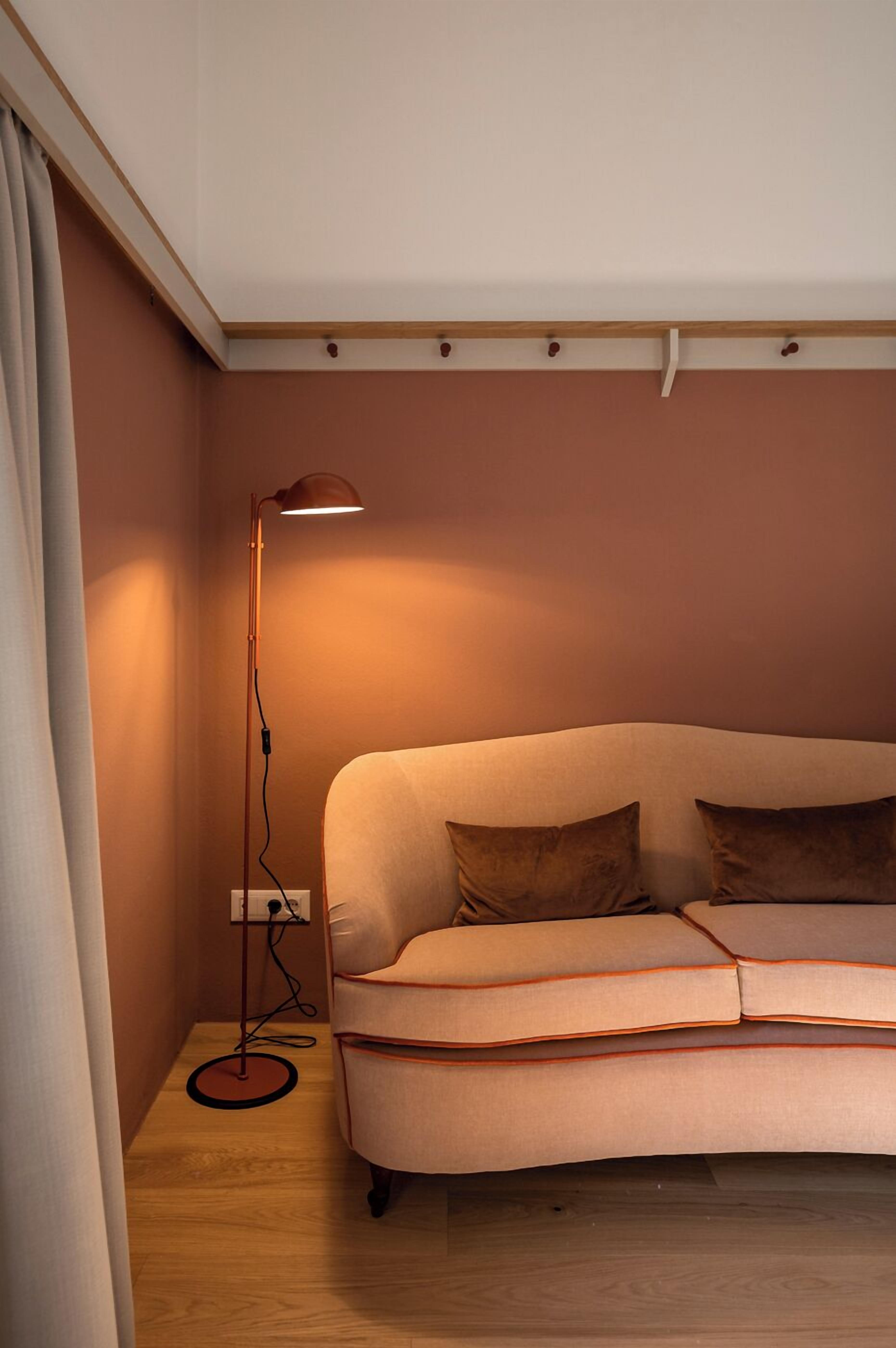 Quarto com sofá, luminária de chão e tomada na parede.