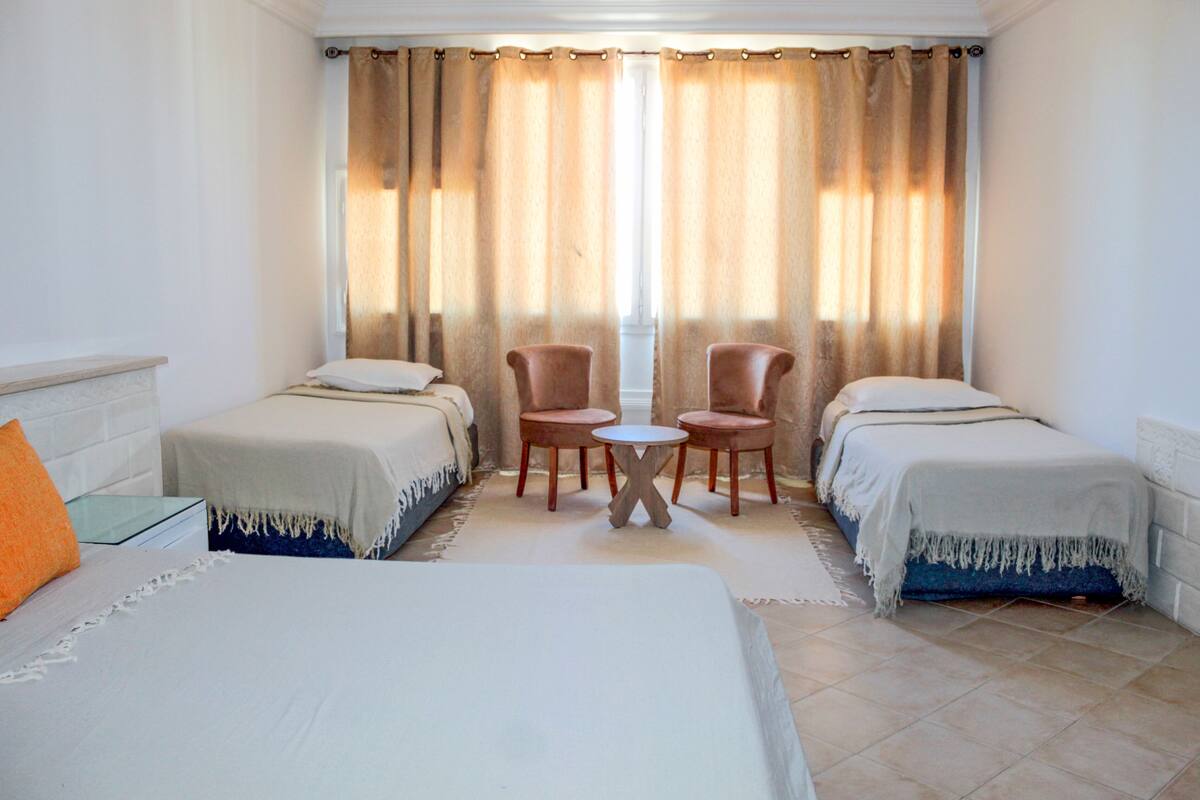 A hotel room with two beds, a small round table, and two chairs.