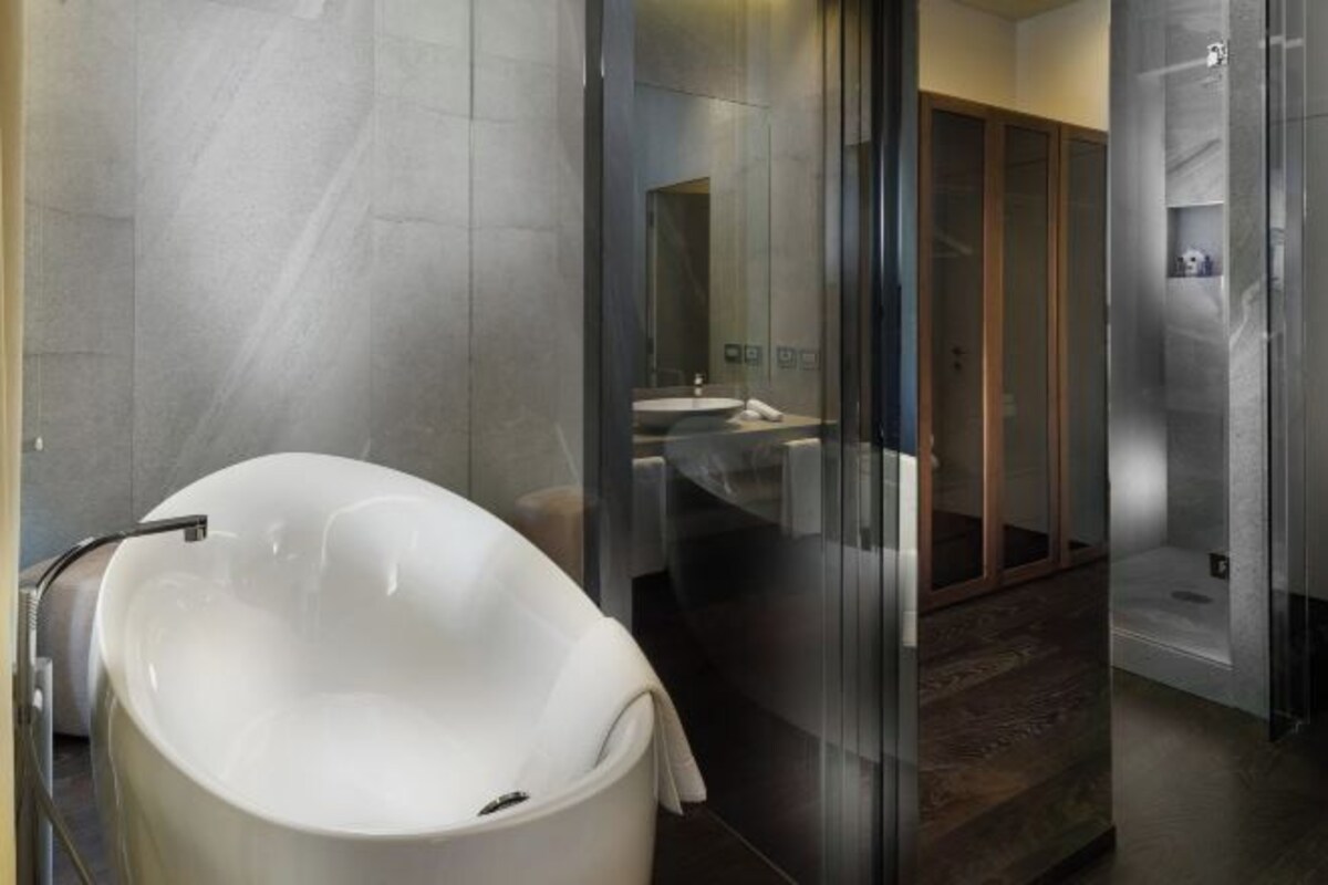 A modern bathroom with a freestanding bathtub, a glass-enclosed shower area, and a visible sink and mirror.