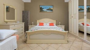 A bedroom with a bed, nightstands, a dresser, a wardrobe, and a painting on the wall.
