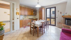 A kitchen with wooden cabinets, a dining table with chairs, a hanging light fixture, and a fireplace.
