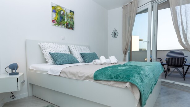 Une chambre moderne avec un lit, un bureau, une chaise et une vue sur l’extérieur.
