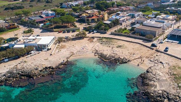 An aerial view of a coastal area with clear turquoise waters, rocky shoreline, and residential buildings. - 3196 Villa Angela by Barbarhouse (Nardò)