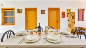 A dining table set with plates, cutlery, and glasses, flanked by wooden doors and framed artwork. - 3196 Villa Angela by Barbarhouse (Nardò)