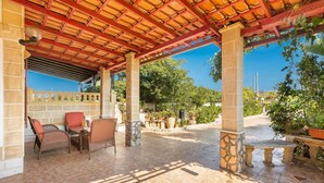 An outdoor patio area with a tiled floor, wooden furniture, and potted plants. - 3196 Villa Angela by Barbarhouse (Nardò)
