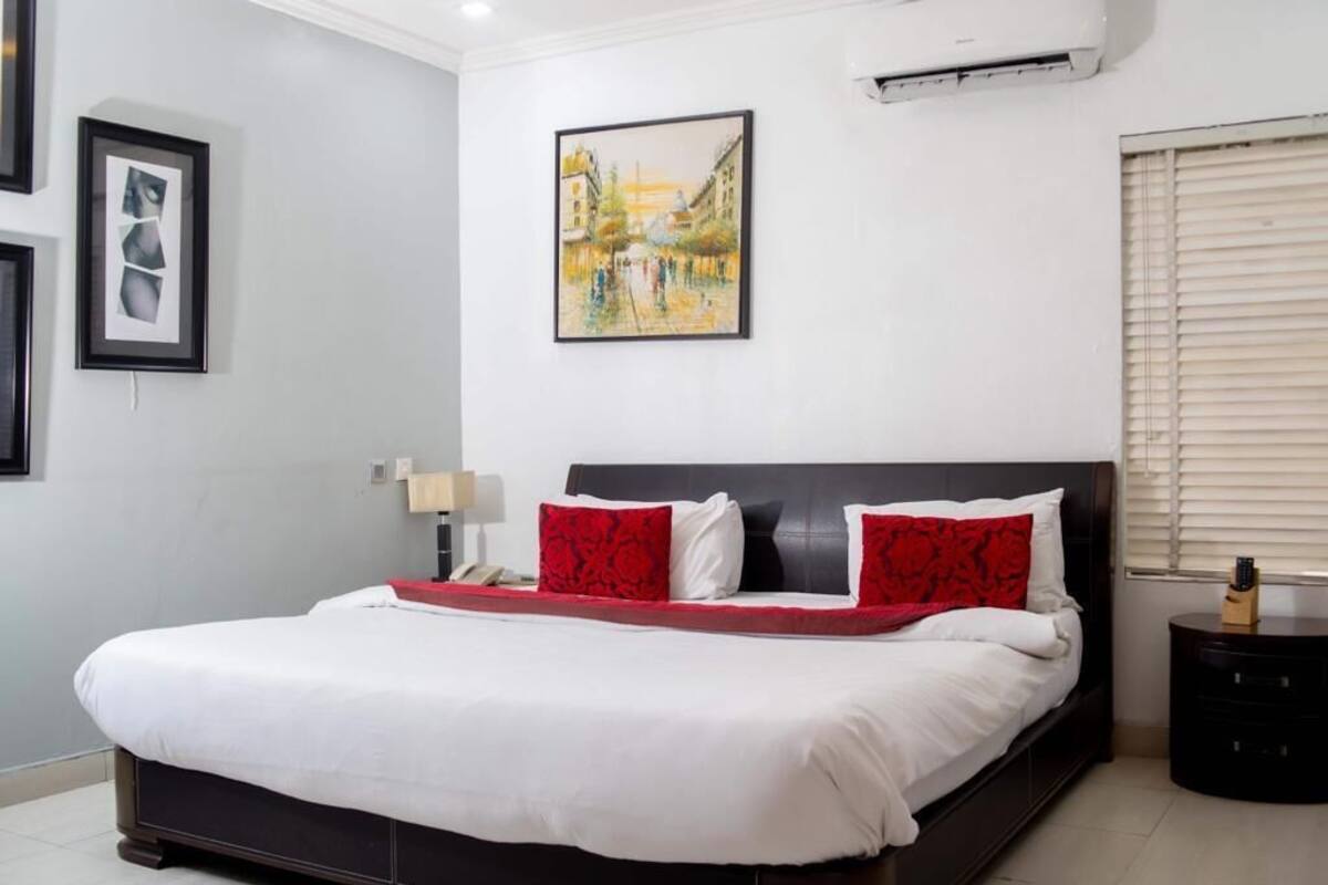 Ein Schlafzimmer mit einem großen Bett, einem Bild an der Wand und einem Fenster mit Jalousien.