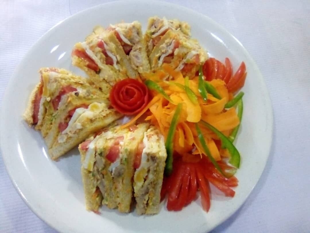 A plate with a slice of quiche and a decorative arrangement of vegetables.