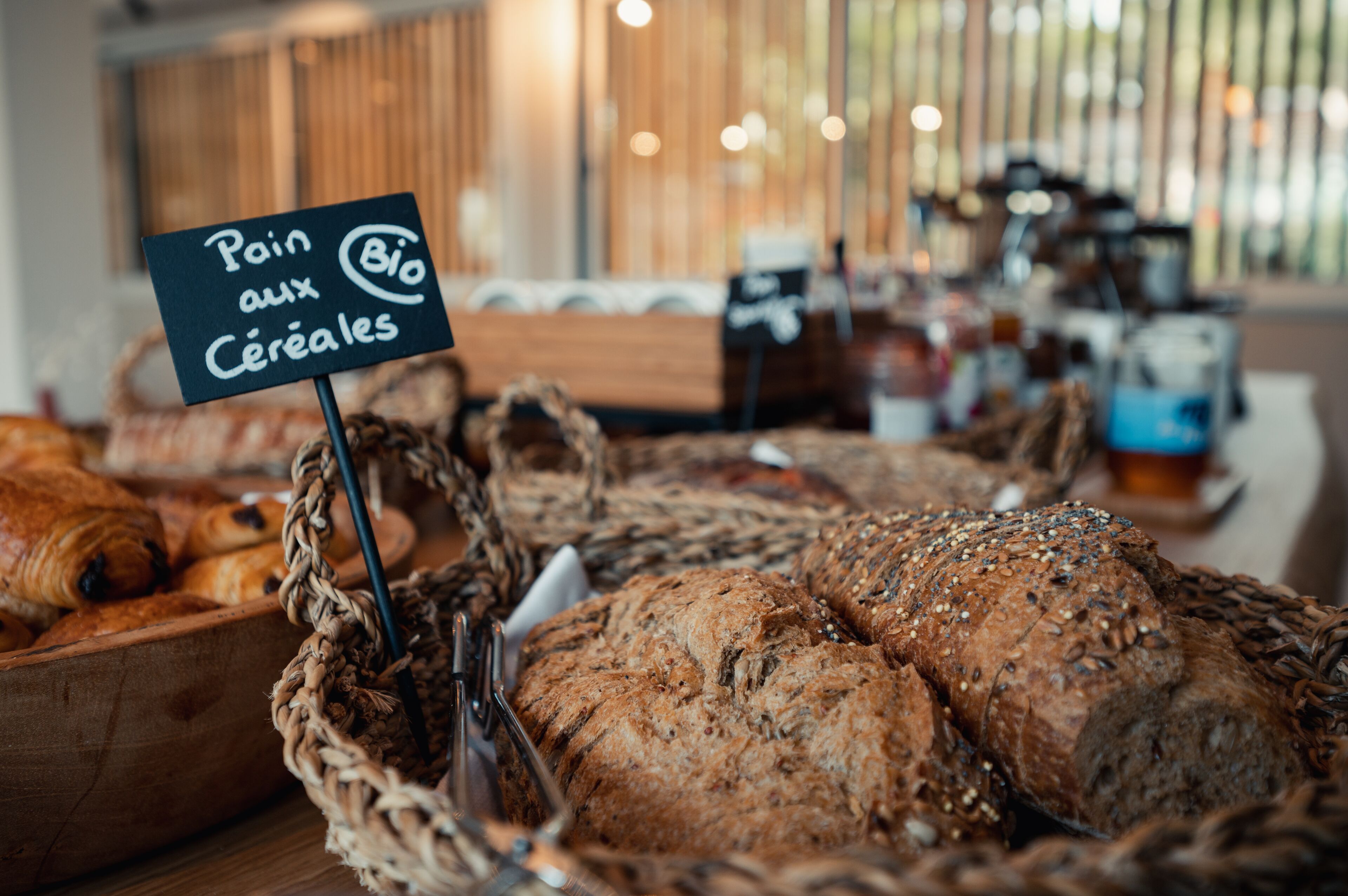 Une vitrine de boulangerie présentant divers pains et pâtisseries, dont un panneau indiquant « Pain aux céréales ».