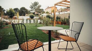 A patio with two chairs and a table, surrounded by a well-maintained lawn and a wooden pergola.