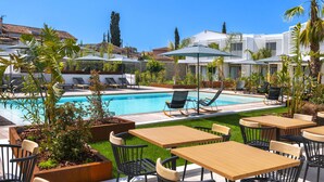 Un espace aménagé au bord de la piscine, avec des chaises longues, des tables et des parasols.