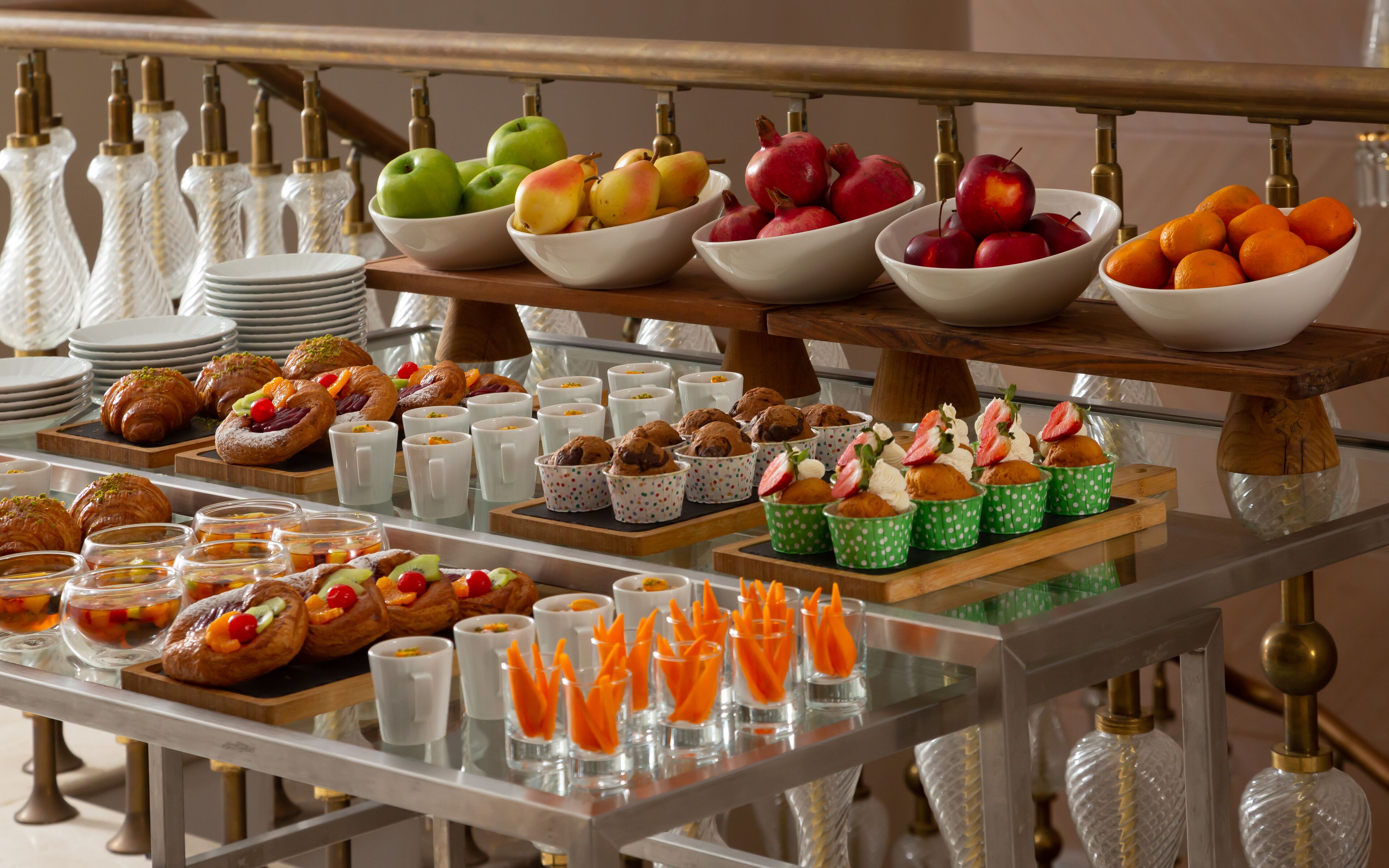 Ein reichhaltiges Buffet mit einer Auswahl an Speisen, darunter Obst, Gebäck und Getränke.