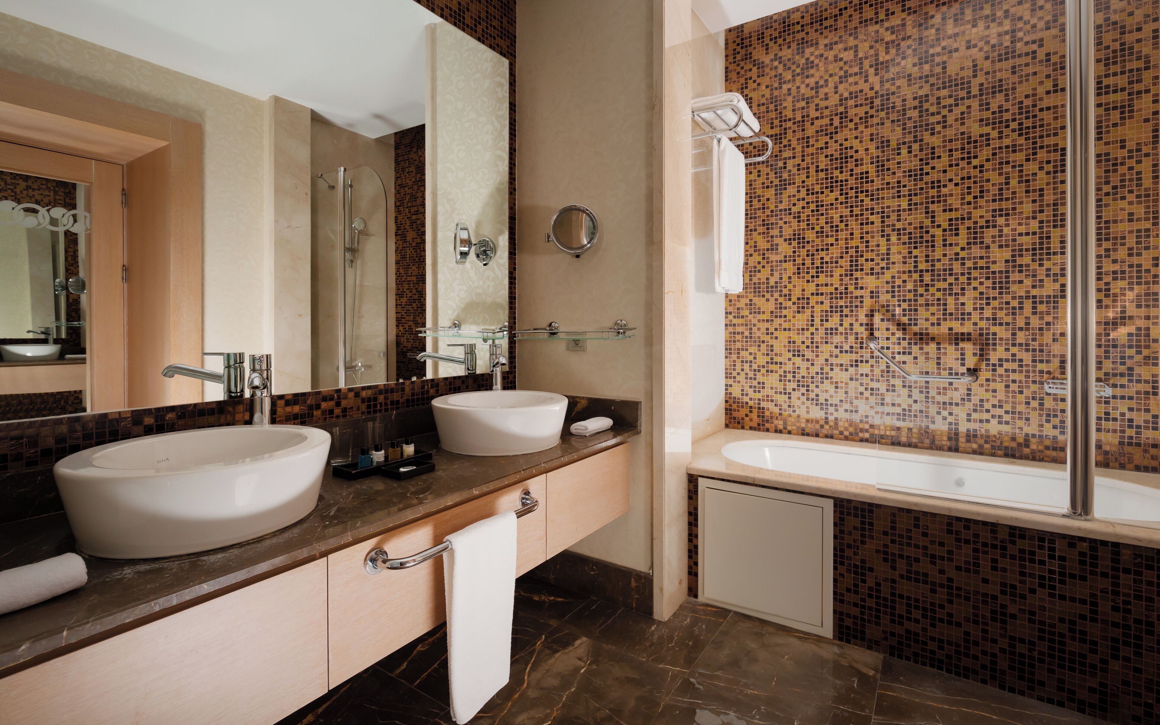 Ein modernes Badezimmer mit zwei Waschbecken, einer Dusche und einem großen Spiegel.