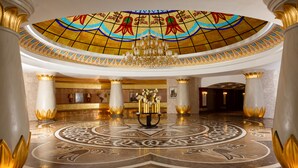 A grand lobby with a large chandelier, a reception desk, and a decorative floor pattern. - Badamdar Hotel and Residences (Baku)