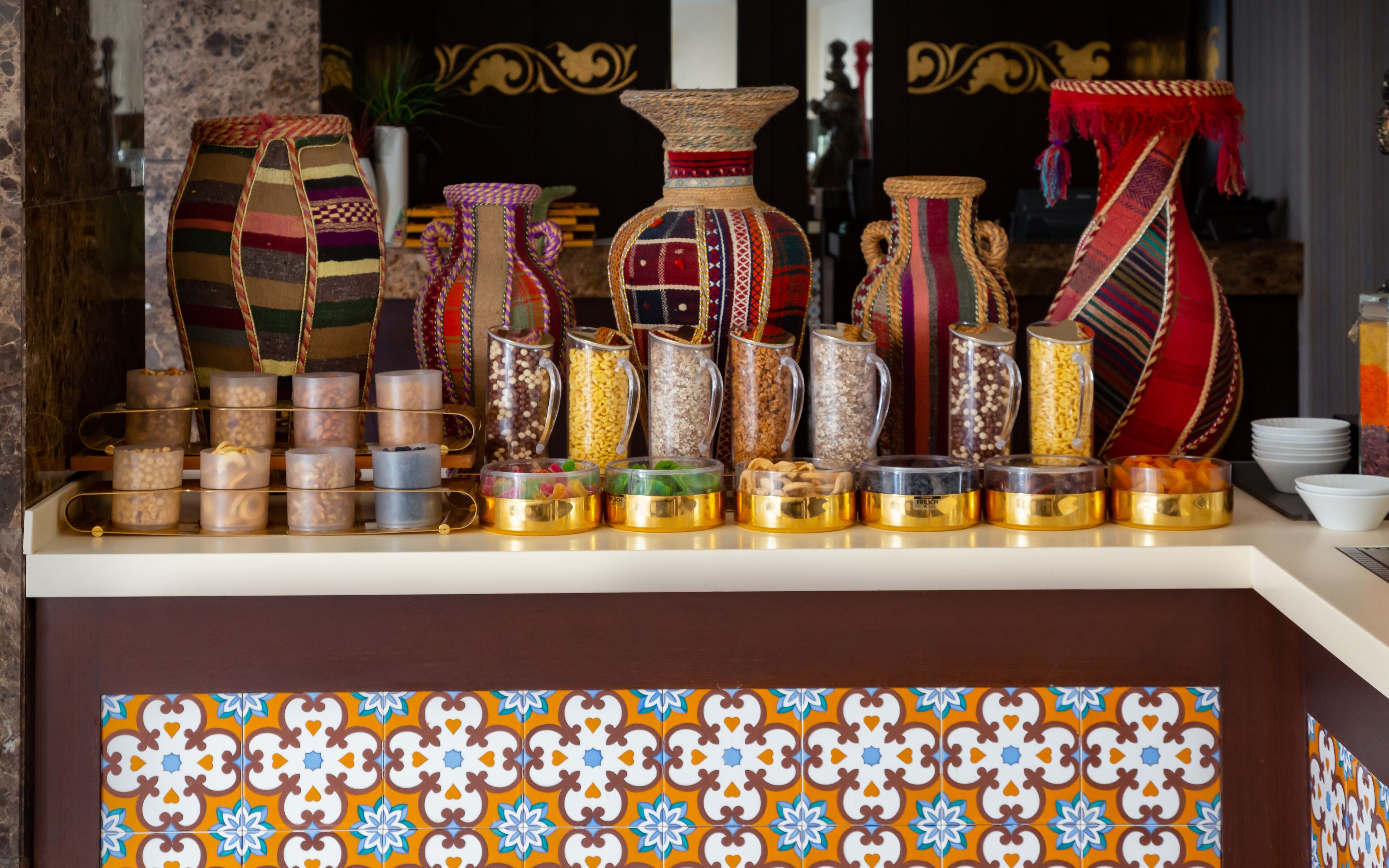 A display of various containers and jars with colorful patterns, arranged on a counter with a decorative tile border.