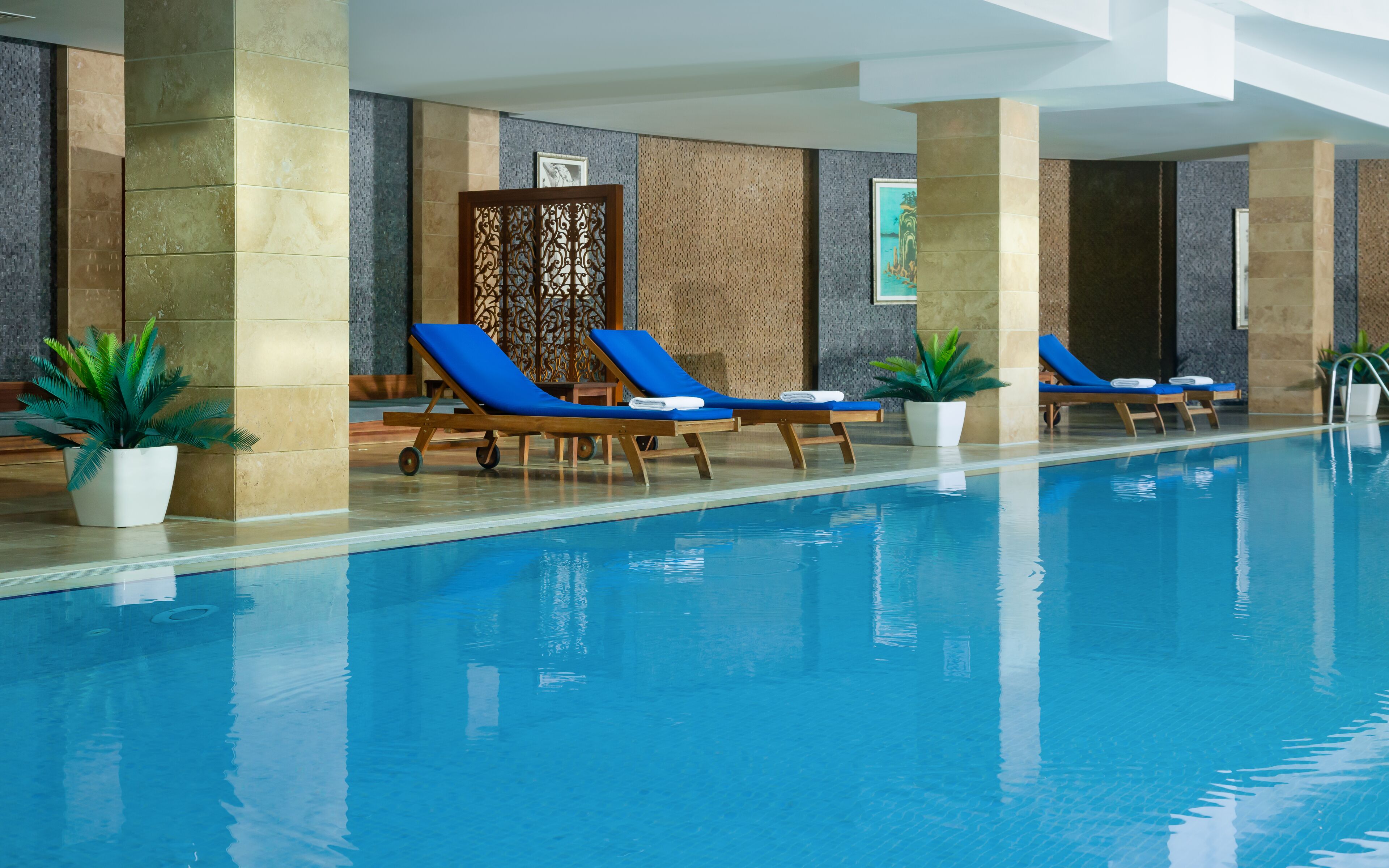 A swimming pool with lounge chairs and potted plants.