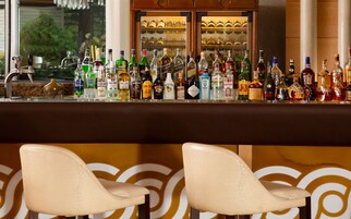 Een bar met verschillende drankflessen en twee witte barkrukken.