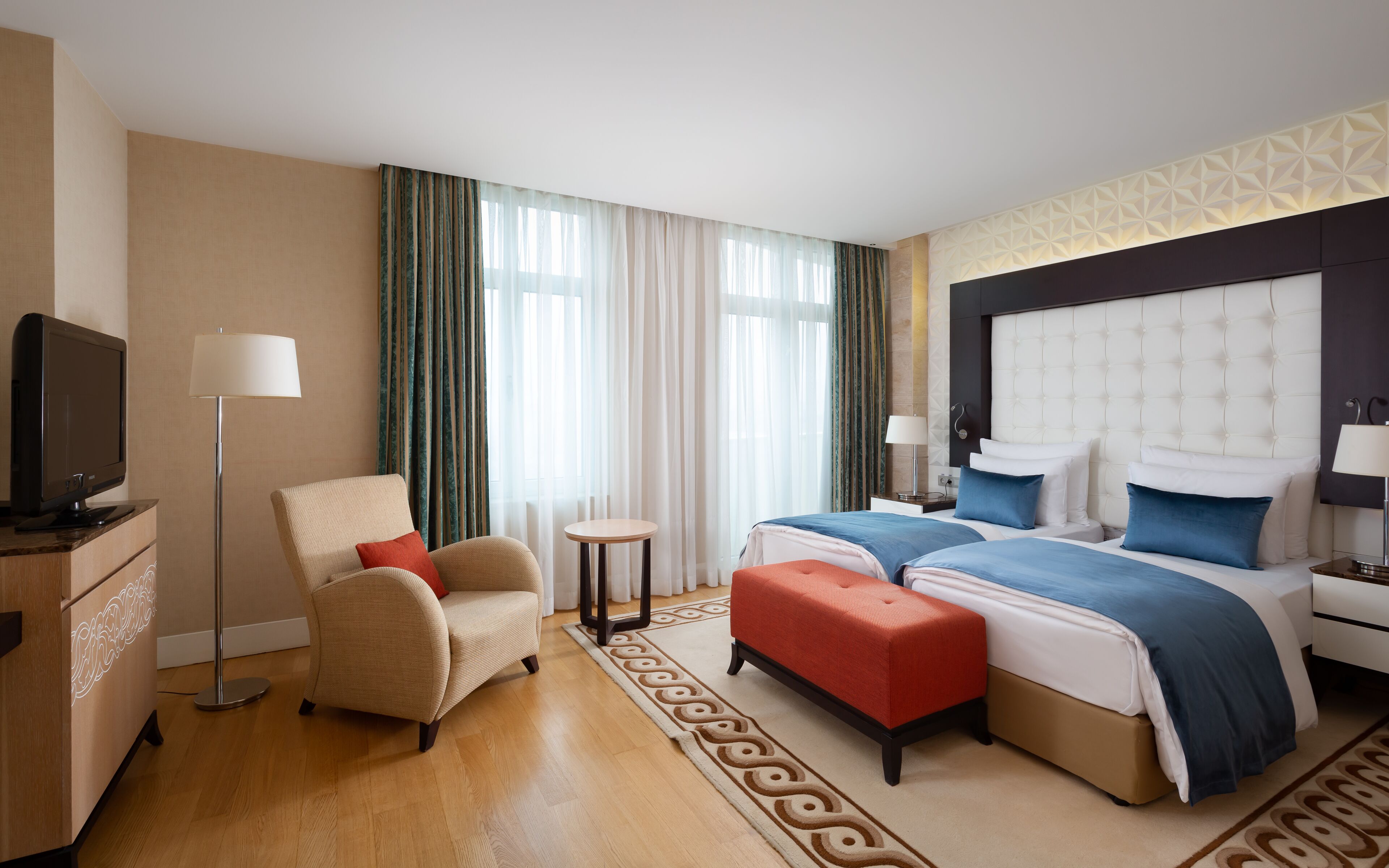 Una habitación de hotel con cama, una silla, televisión y una mesita.