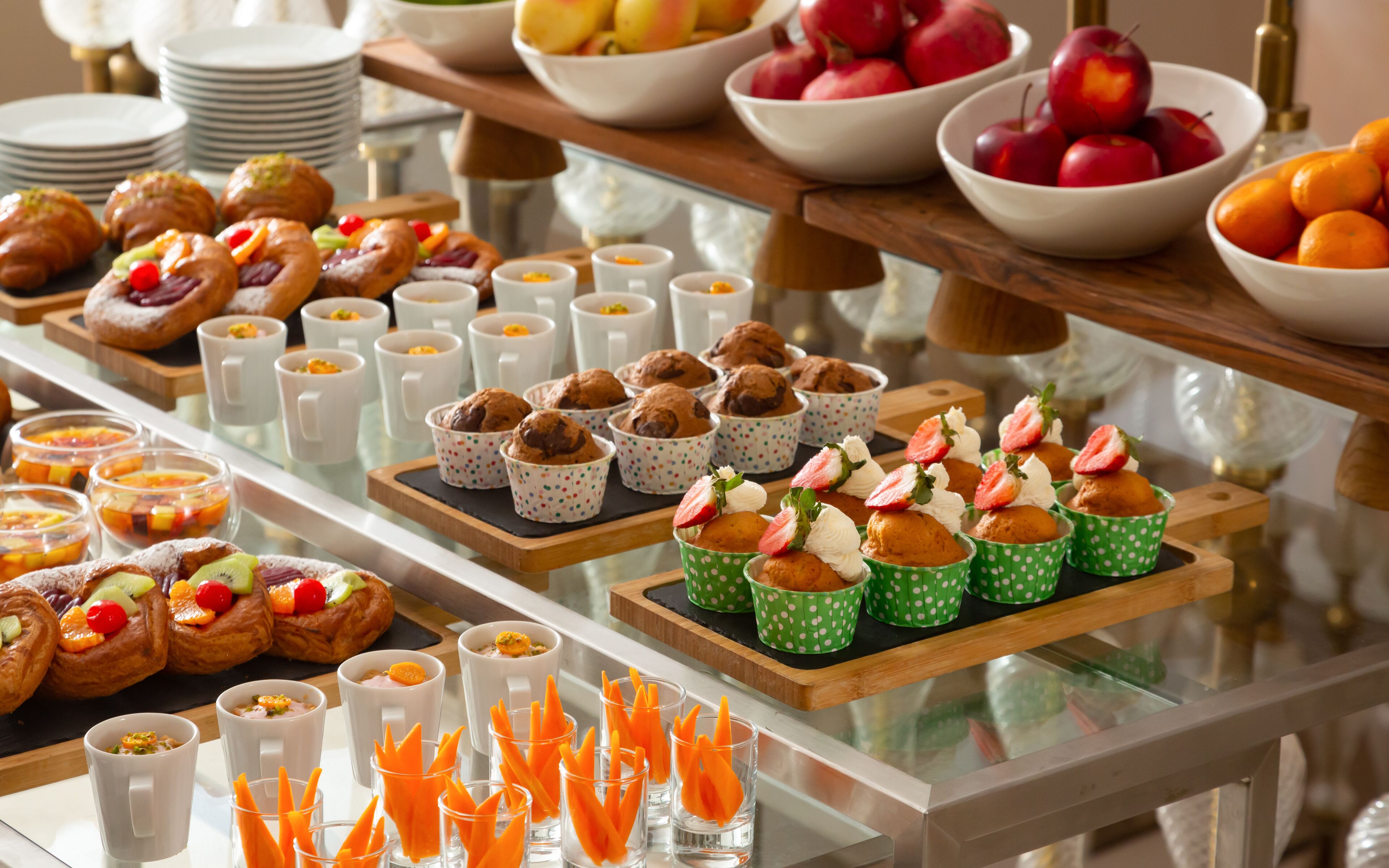 A buffet with various food items including pastries, fruits, and desserts.