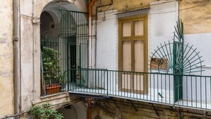 A balcony with a green metal railing, a potted plant, and a window with a wooden frame. - Art Apartment at Sanit by Wonderful Italy (Naples)